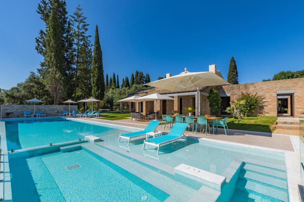 a swimming pool with blue chairs and a house at Villa Ionica in Kontokali
