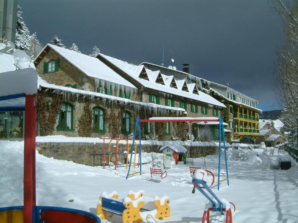 un parque infantil cubierto de nieve frente a un edificio en Hotel Adsera, en La Molina