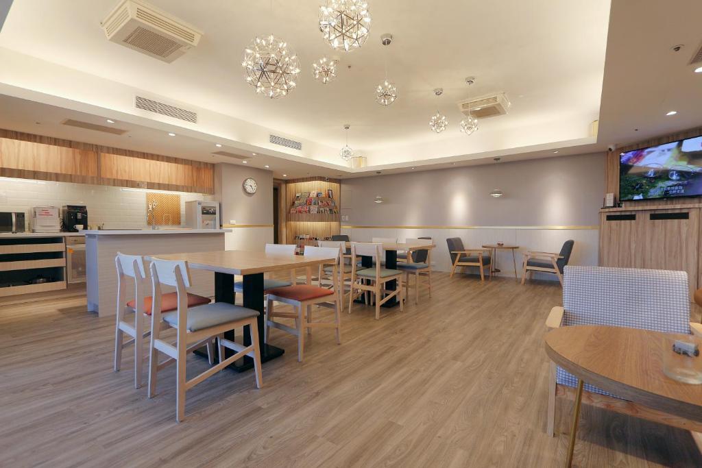 a dining room with tables and chairs and a kitchen at Sky19 Hotel in Taipei