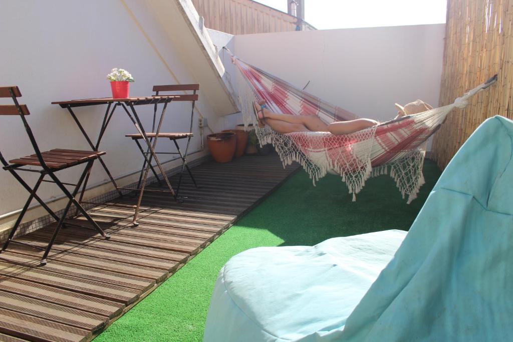 uma rede de descanso numa varanda com uma mesa e cadeiras em Watermark Surf House em Espinho