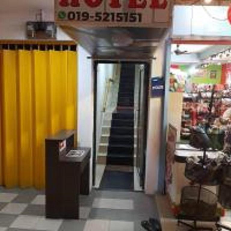 une entrée avec une porte jaune et des escaliers dans un magasin dans l'établissement Emerald Inn, à Brinchang