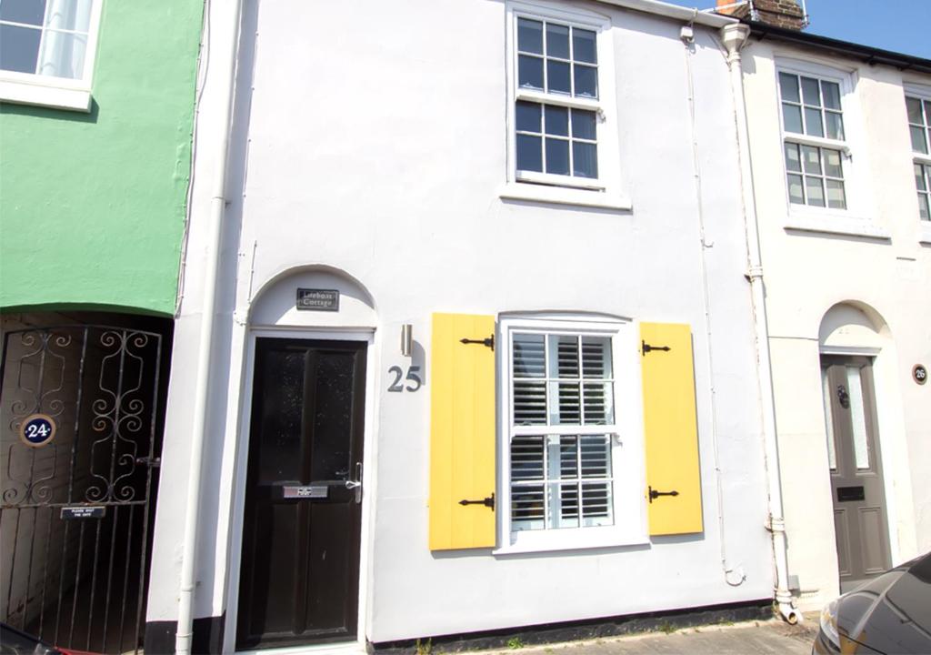 a white house with yellow doors on a street at Lifeboat Cottage in Deal