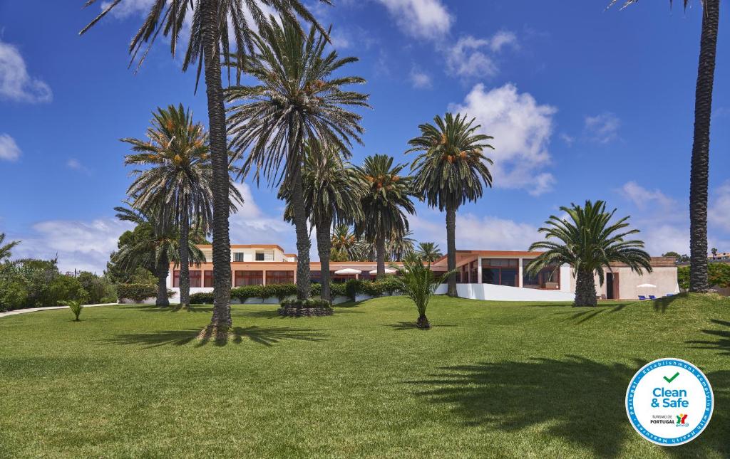 a house with palm trees in front of a yard at Hotel Porto Santo & Spa in Porto Santo