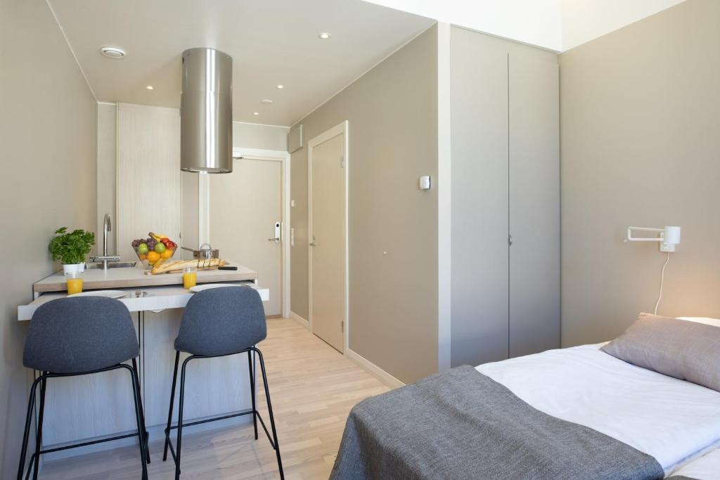 ein Schlafzimmer mit einem Bett und 2 Stühlen sowie eine Küche in der Unterkunft Forenom Aparthotel Vaasa in Vaasa