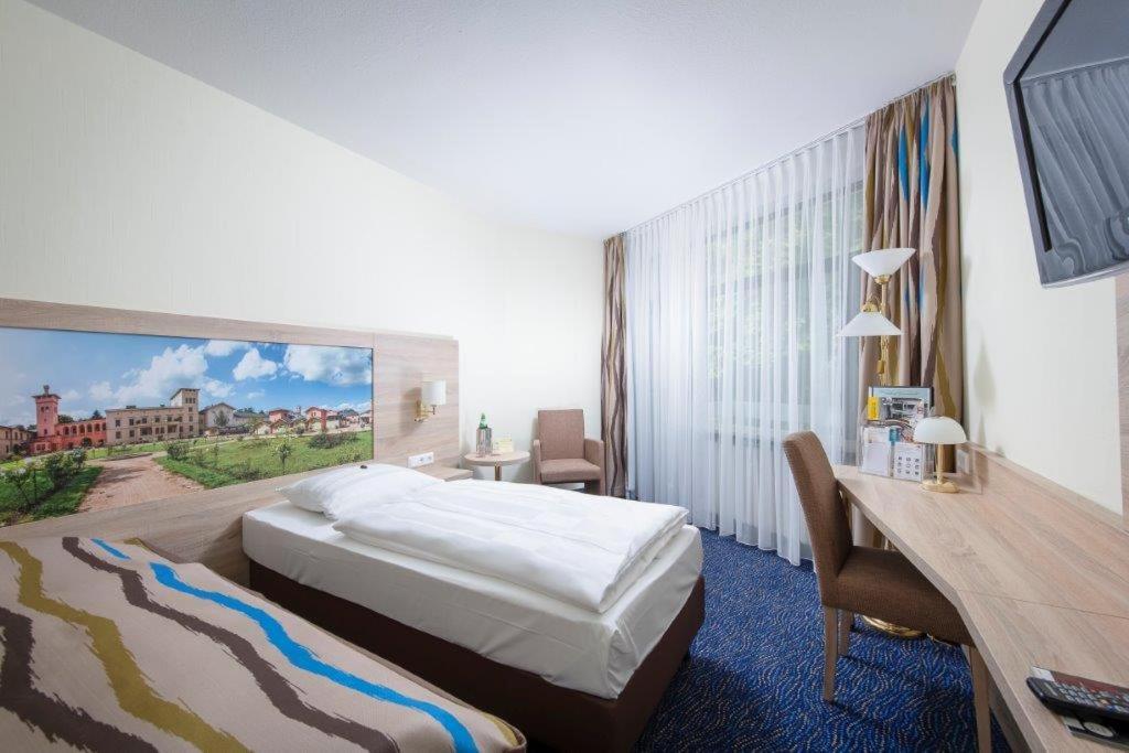 ein Hotelzimmer mit einem Bett und einem Gemälde an der Wand in der Unterkunft Seehotel Grunewald in Berlin