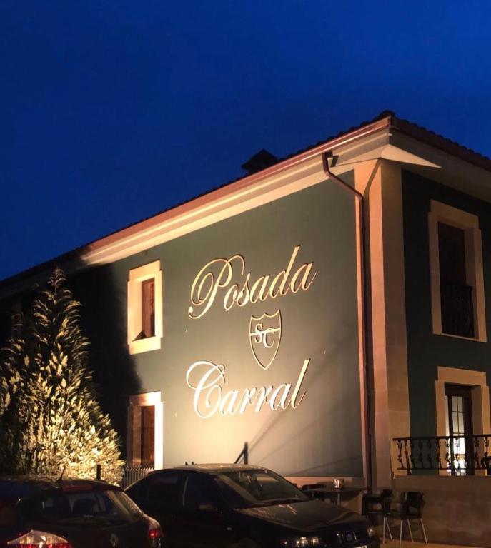 a sign on the side of a building at night at posada carral cabarceno in La Concha