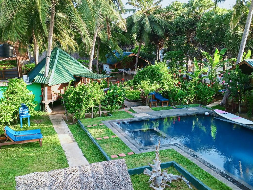 einen Pool in einem Garten mit Palmen in der Unterkunft Bella Nilaveli Beach in Nilaveli