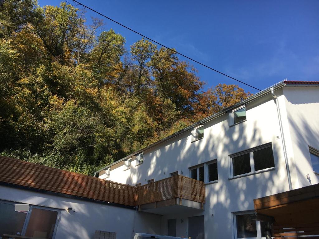 ein weißes Gebäude mit seitlicher Terrasse in der Unterkunft Ferienwohnungen Lamisto am Waldesrand in Neckartenzlingen