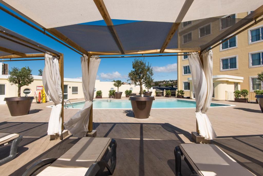a patio with chairs and a pool in a building at Vila Galé Estoril in Estoril