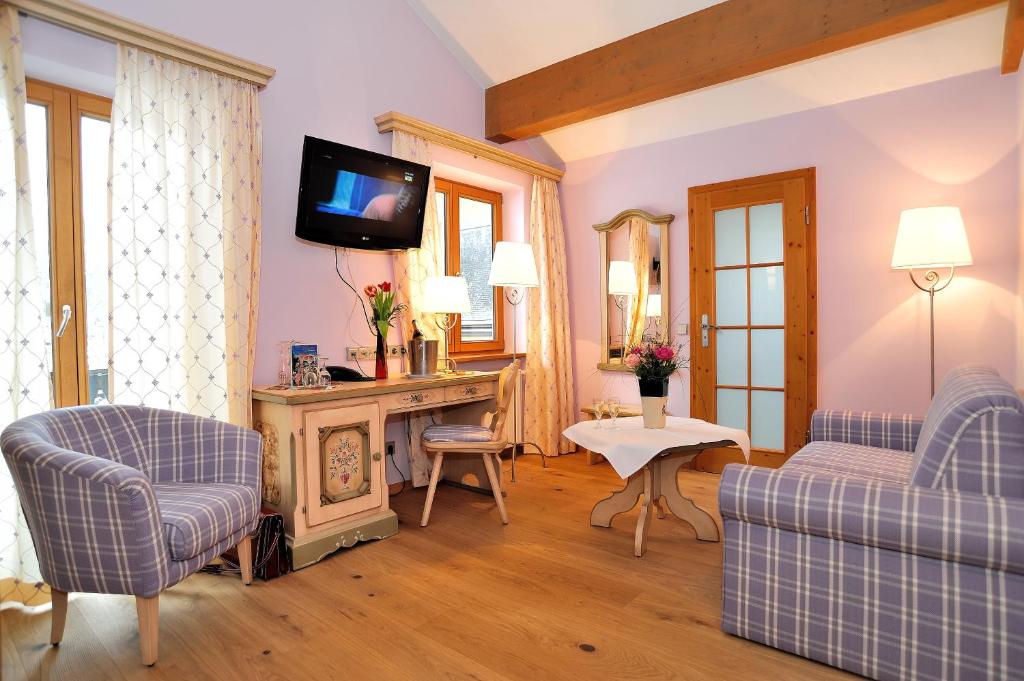a living room with two couches and a tv at Landhotel Böld Oberammergau in Oberammergau