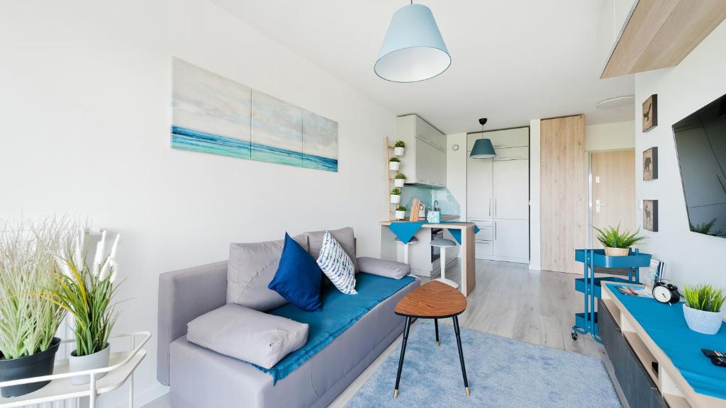 een woonkamer met een blauwe bank en een tafel bij Apartamenty Sun & Snow Konopnicka City in Krakau