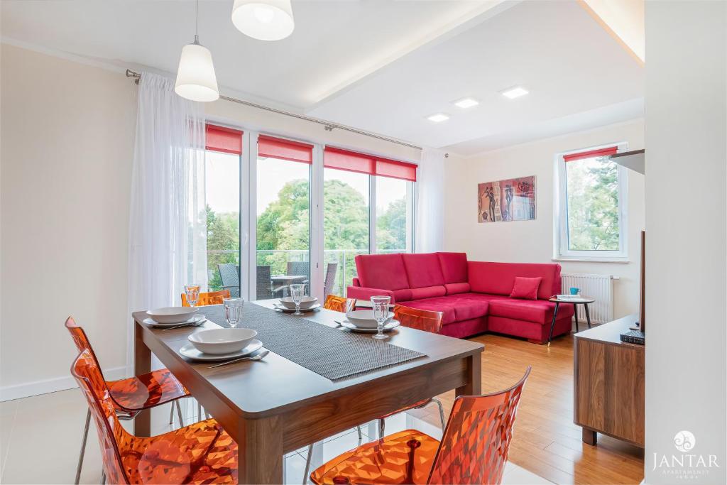 a dining room with a table and a red couch at Jantar Apartamenty - Wyspa Solna City Center in Kołobrzeg