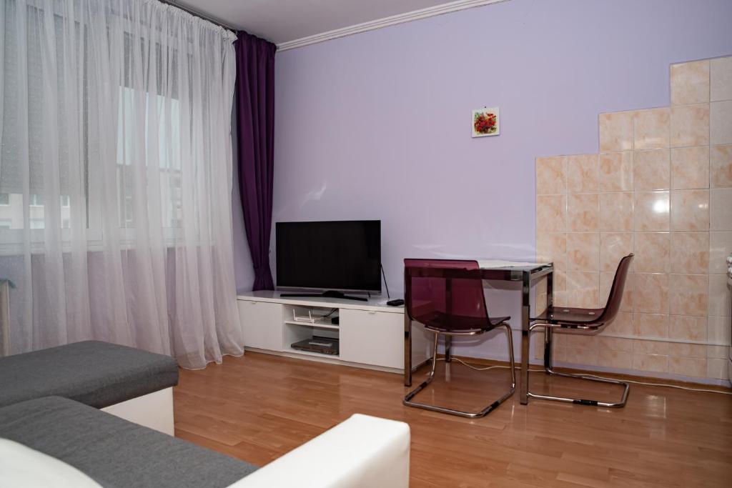 sala de estar con TV, mesa y sillas en LOVELY ONE BEDROOM APARTMENT en Nové Zámky