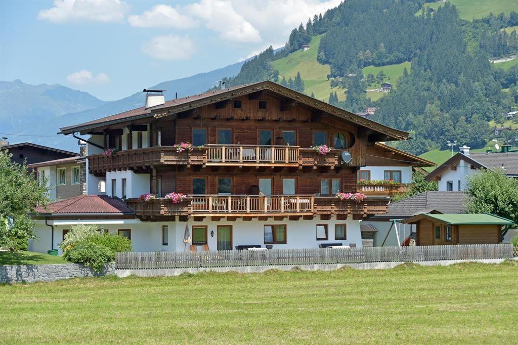 uma grande casa de madeira com uma varanda num campo em Wechselberger Johanna em Schwendau