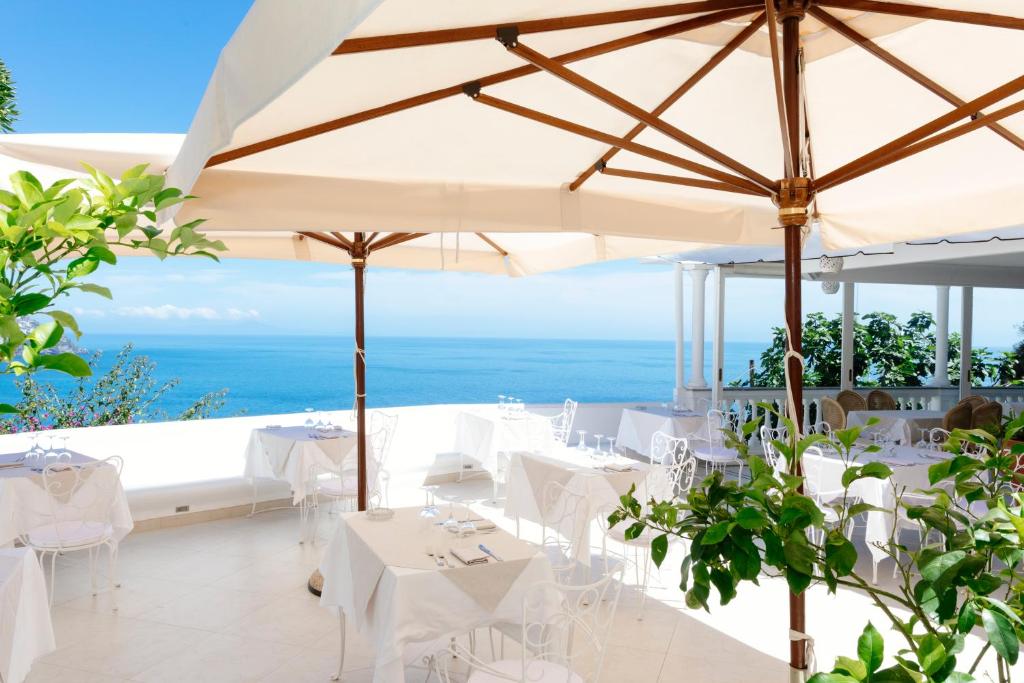 un restaurante con mesas blancas y vistas al océano en Hotel Conca d'Oro, en Positano
