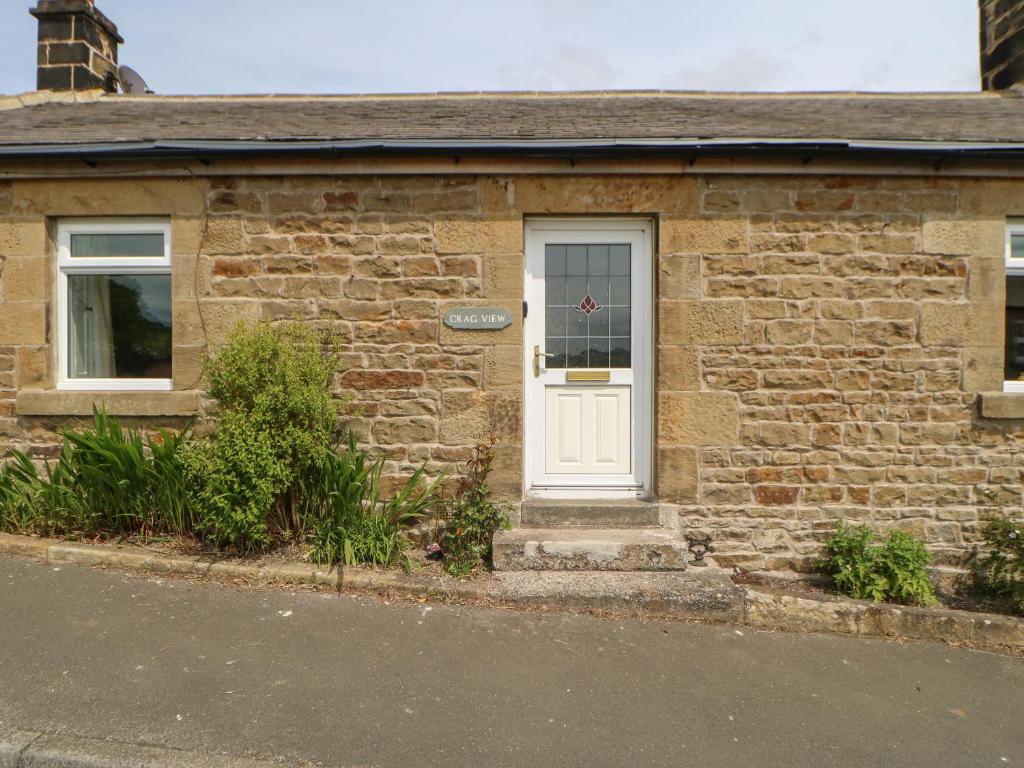 a brick house with a white door and windows at Crag View in Hexham