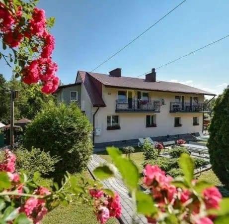 a house with a yard with flowers in front of it at Noclegi U Renaty Solina in Solina