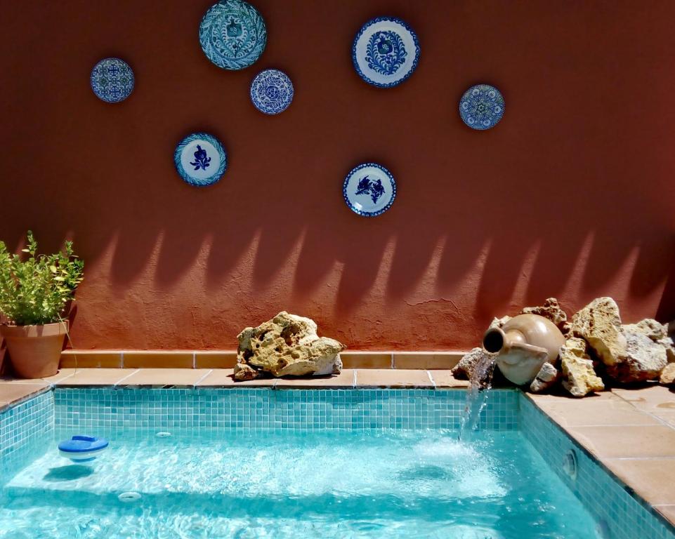 a swimming pool with an elephant and plates on a wall at CASA RURAL "LA CASITA" para 2 personas in Ronda