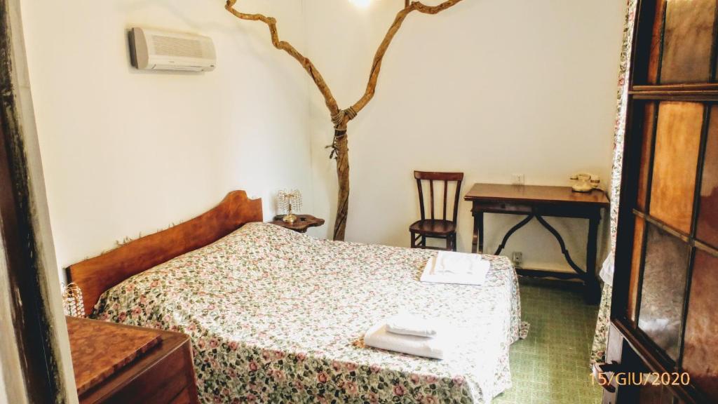 een slaapkamer met een bed en een tafel en een boom bij La Casa del Grillo in Viterbo