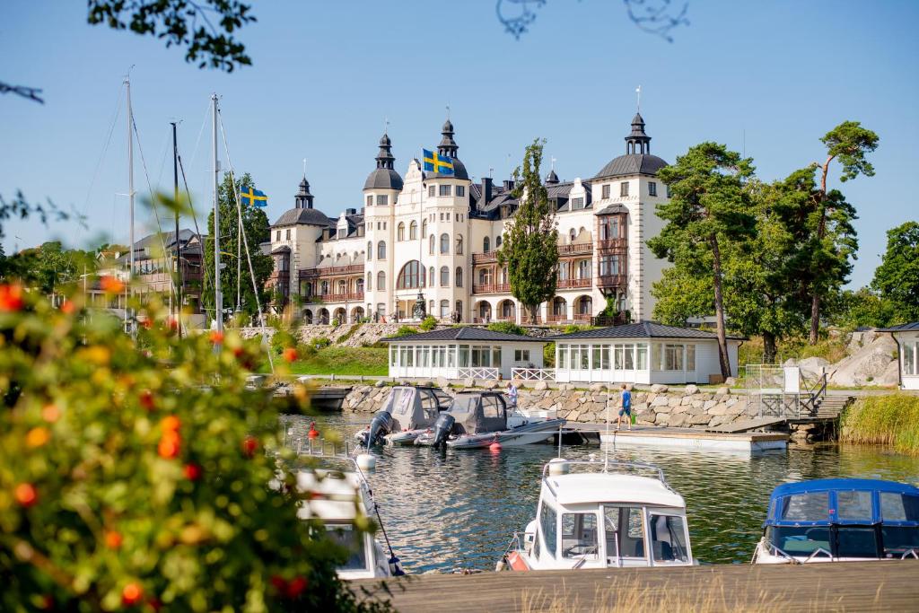 un grand bâtiment avec des bateaux amarrés dans un port dans l'établissement Grand Hotel Saltsjöbaden, à Saltsjöbaden