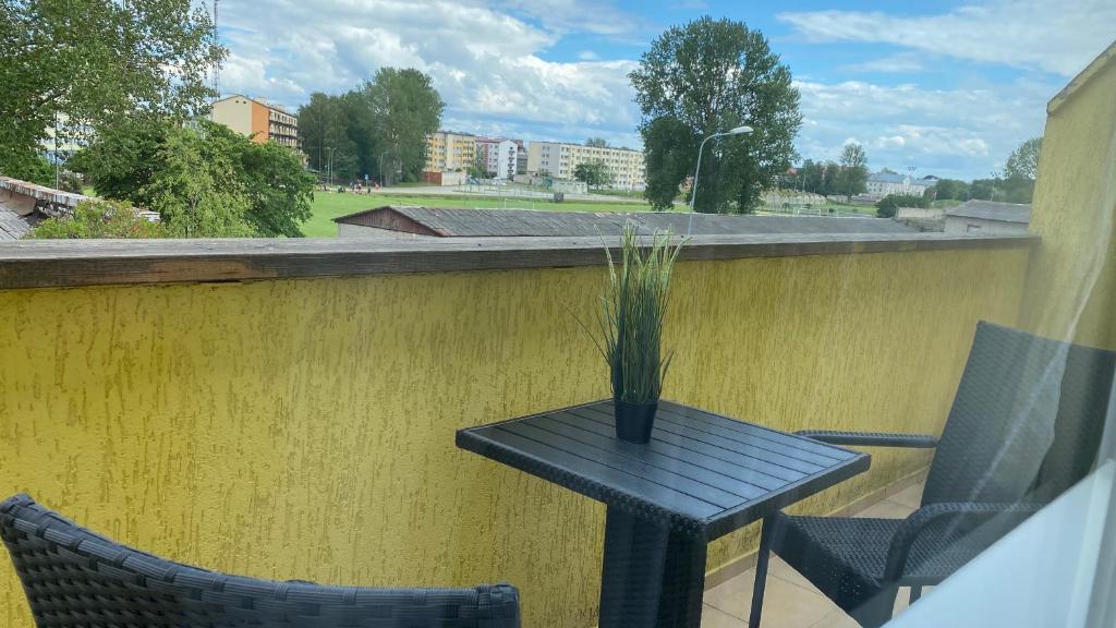 een zwarte tafel en 2 stoelen op een balkon bij Zvejnieku Alejas Apartment in Liepāja