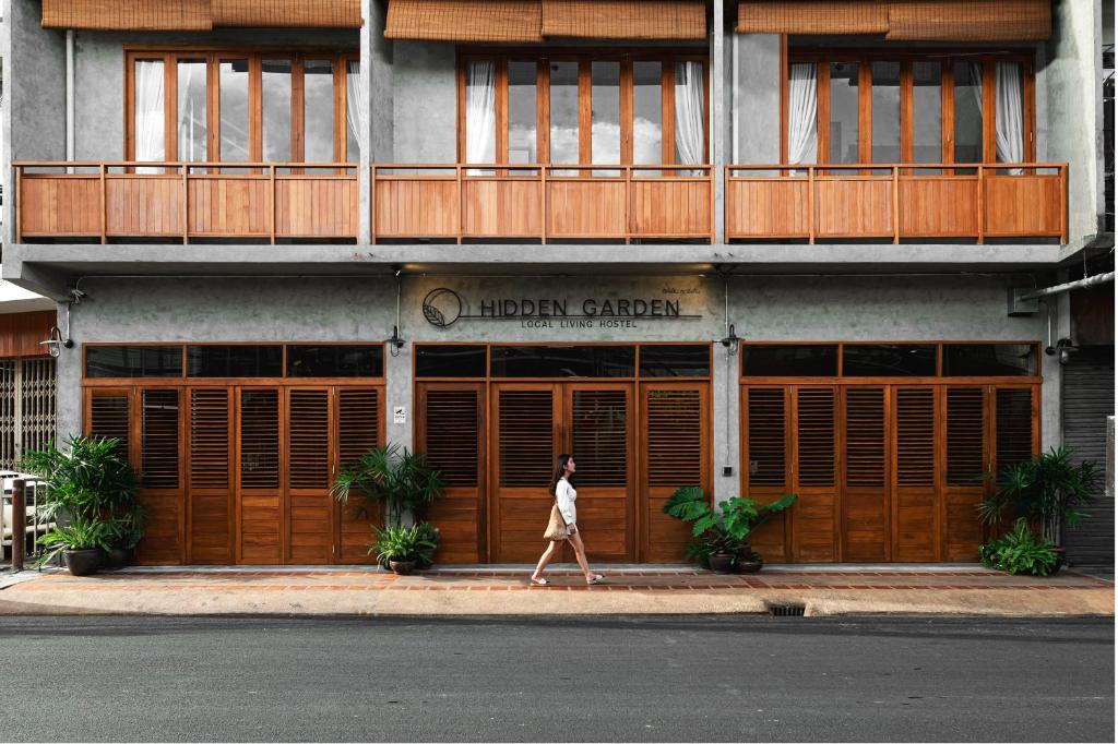 a woman walking in front of a building at Hidden Garden Hostel in Chiang Mai