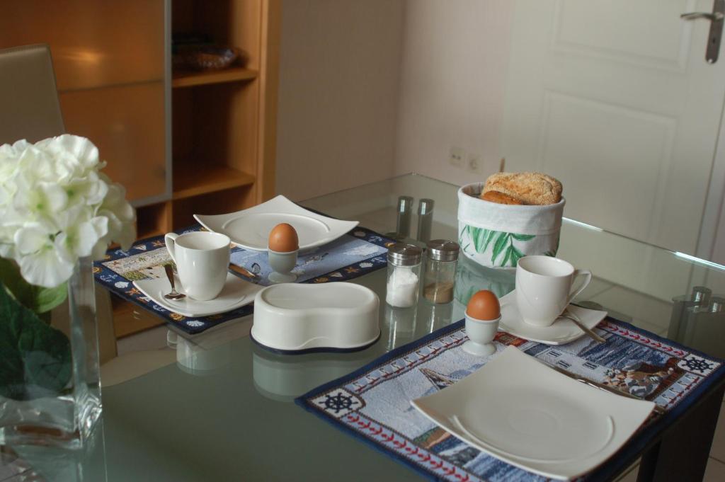 una mesa con platos y huevos y un jarrón de flores en Ländlich ruhig 10 km vor Rostock, en Dummerstorf