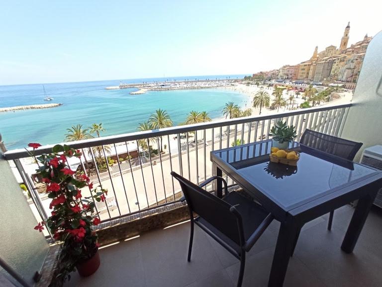 einen Balkon mit einem Tisch und Strandblick in der Unterkunft APPARTEMENT TERRASSE VUE MER Sea view terrace apartment "Etoile de Mer" in Menton