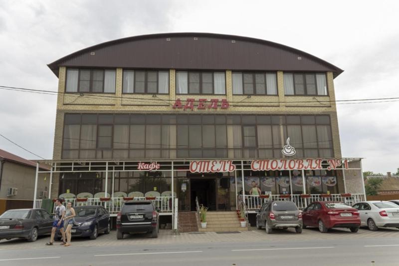 a building with cars parked in front of it at Отель Адель in Dolzhanskaya