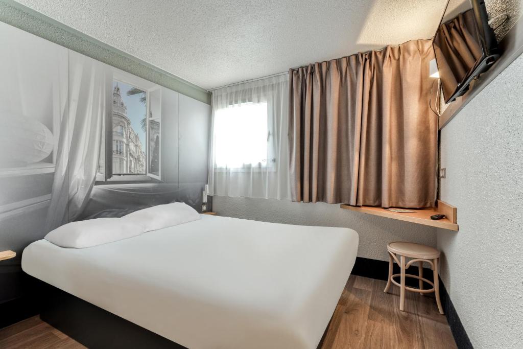 een slaapkamer met een wit bed en een raam bij B&B HOTEL Narbonne 2 in Narbonne