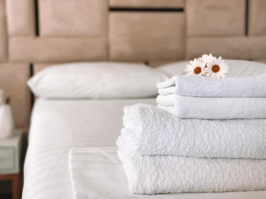 a stack of towels on a bed with a flower on top at ALEVRA in Dhërmi