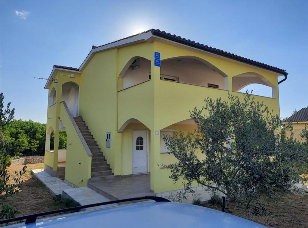 uma casa amarela com um carro à frente em Apartman Tin em Vir