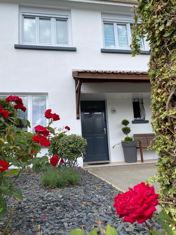 Uma casa branca com flores vermelhas à frente. em Chambres d'hotes Welcome Trépied em Cucq