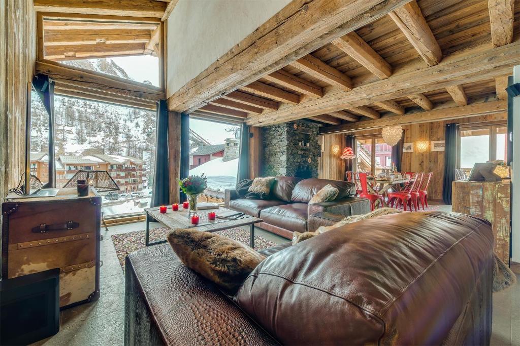 a living room with a leather couch and a table at Madame Vacances Le Chalet Denali in Val-d'Isère