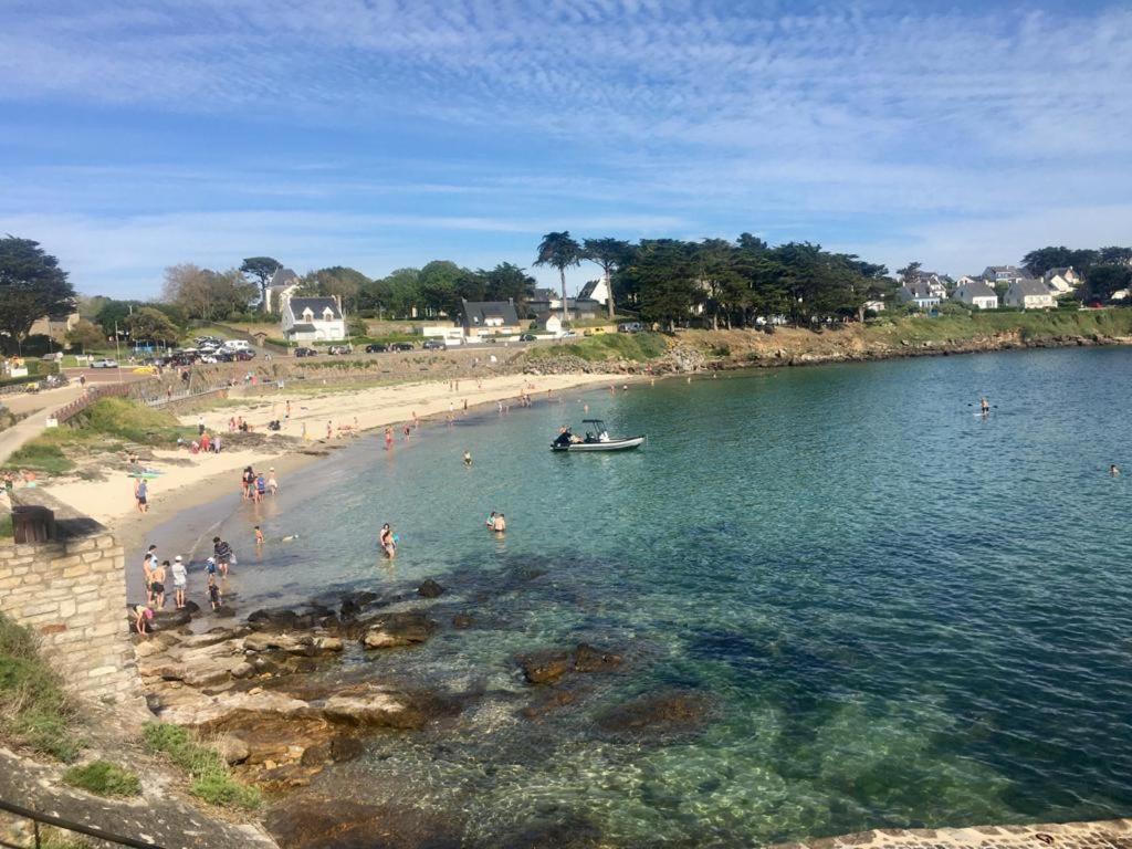 people on a beach with a boat in the water at La petite Escarpolette in Arzon