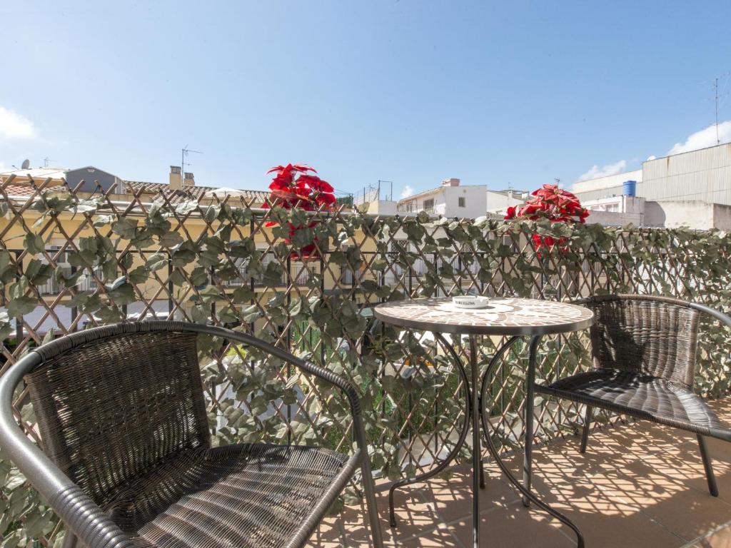two chairs and a table on a balcony with red roses at POSEIDÓN Bonito y cuidado apartamento con wifi gratis in Pineda de Mar