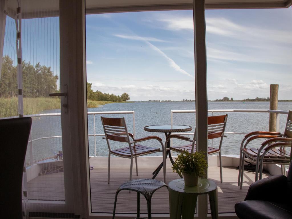 a porch with chairs and a table and a view of the water at Houseboat uitzicht over veluwemeer, natuurlokatie, prachtige vergezichten in Biddinghuizen
