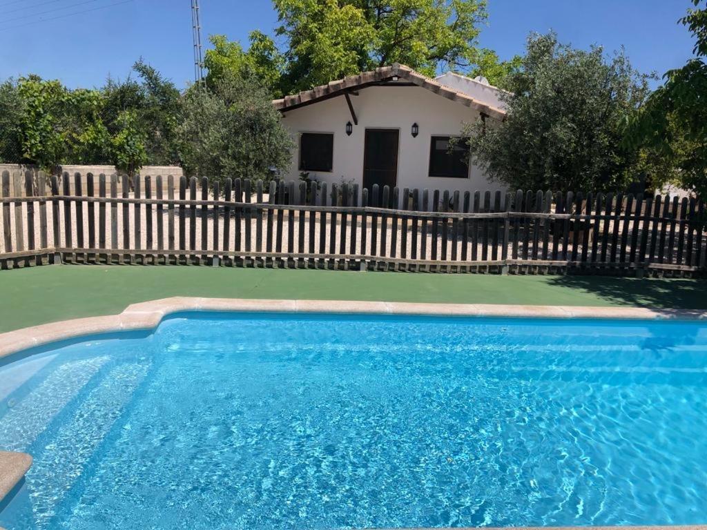 a swimming pool in front of a fence with a house at Casa de Campo Patricia in Priego de Córdoba