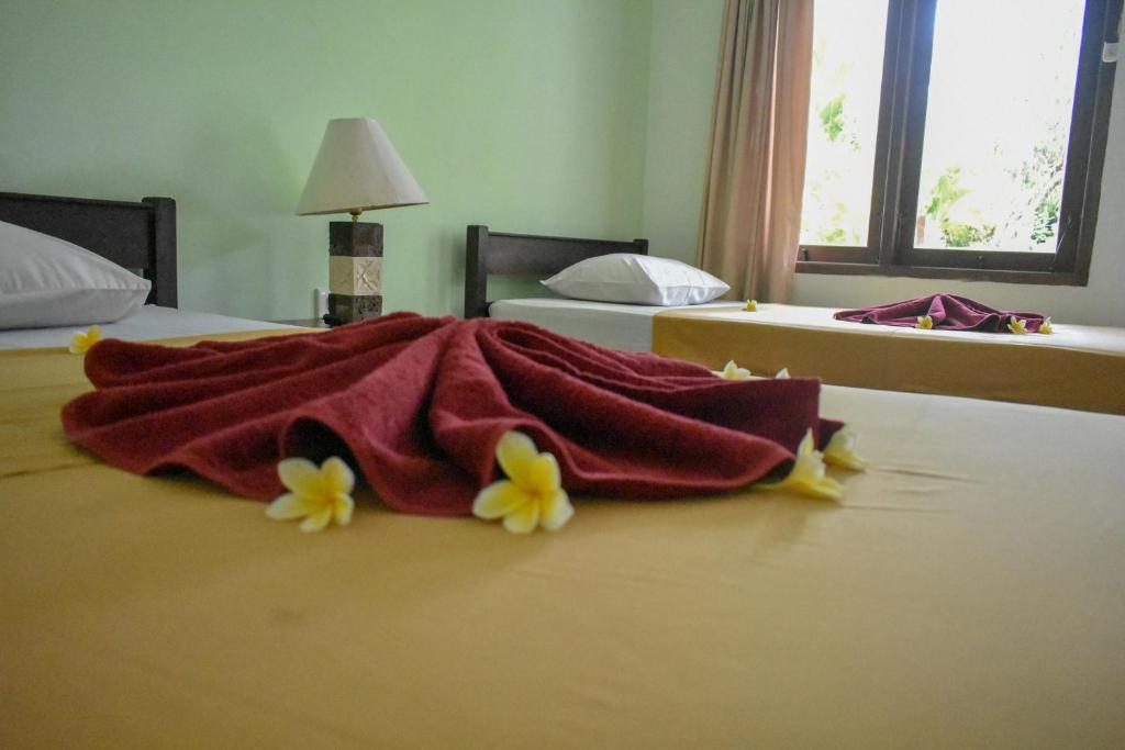 Una manta roja en una cama con flores. en Medori Putih Homestay, en Uluwatu