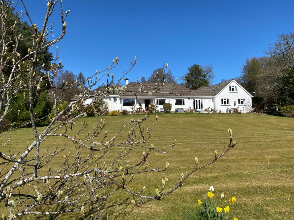 uma casa branca com um grande campo de relva em Coire Glas Guest House em Spean Bridge