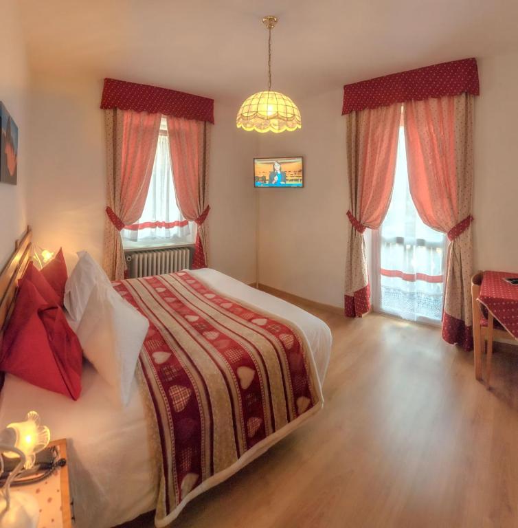 a bedroom with a large bed and two windows at Hotel Garni Suisse in San Martino di Castrozza