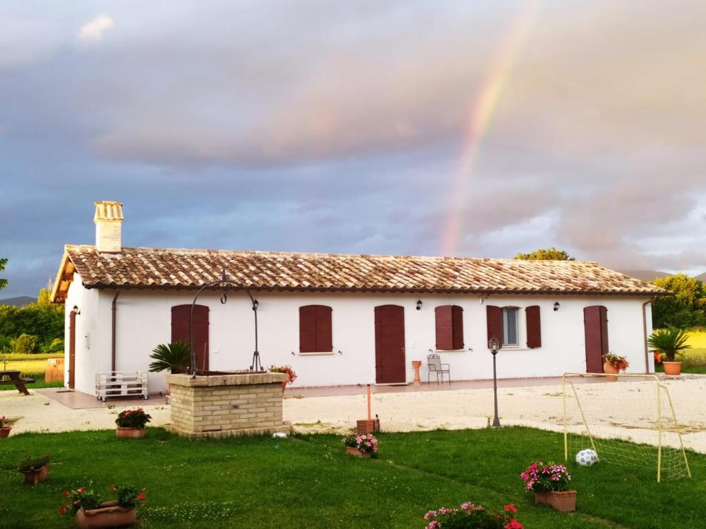 un arco iris sobre una casa blanca con un patio en AGRITURISMO " LE SERRE", en Spello