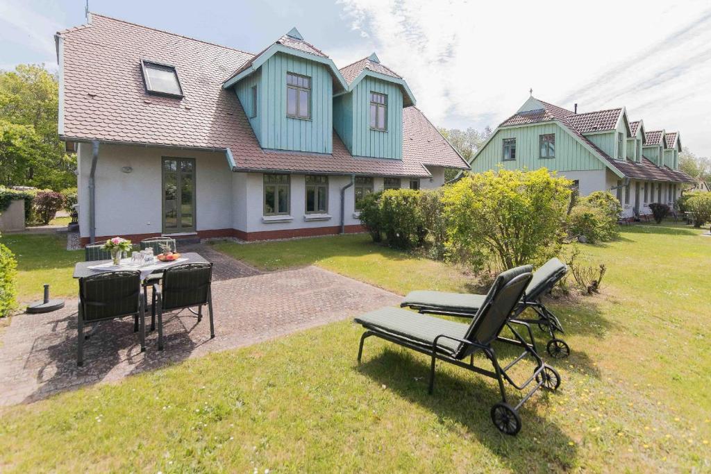 een huis met een stoel en een tafel in de tuin bij Ferienhaussiedlung Strandperlen Küstenhof 4a (Typ IX) in Wustrow