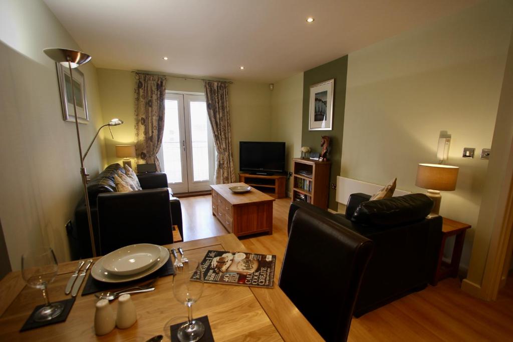 een woonkamer met een tafel en stoelen en een televisie bij City Centre Skeldergate 1 Bed Apartment with Parking in York