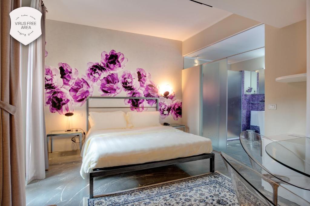 ボローニャにあるイル コンベント デイ フィオーリ ディ セタのベッドルーム1室(ピンクの花が飾られた壁のベッド1台付)