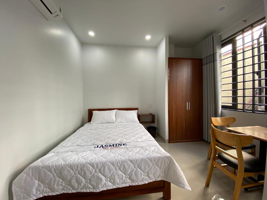 a bedroom with a bed and a table and a window at Jasmine Mini Hotel in Hue