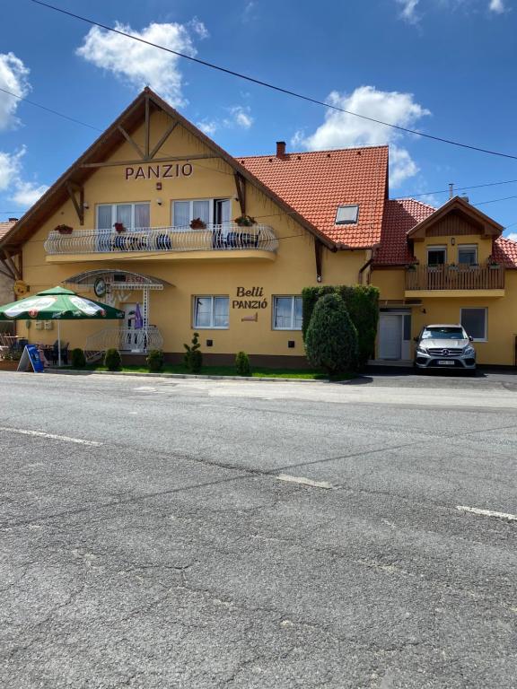 un edificio amarillo con un coche aparcado delante de él en Betli Panzió, en Zalaegerszeg