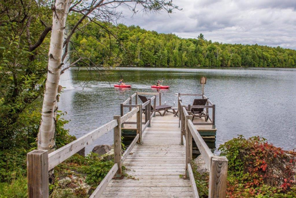 a dock with two people in kayaks on a lake at Auberge du Lac Morency in Saint-Hippolyte
