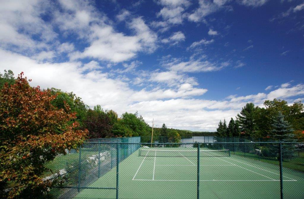 a tennis court with a tennis court at Auberge du Lac Morency in Saint-Hippolyte