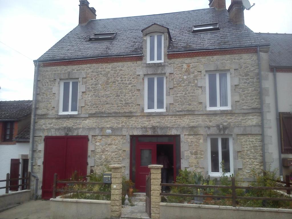 una vieja casa de piedra con una puerta roja en Les Campanules - Neuvy en Sullias, en Neuvy-en-Sullias